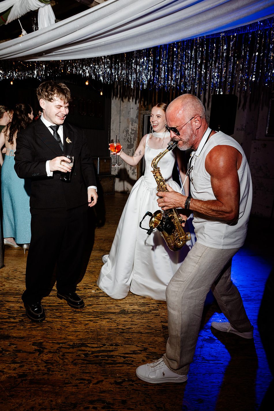 Bride and Paul Martyn dancing as he plays saxophone at a wedding reception
