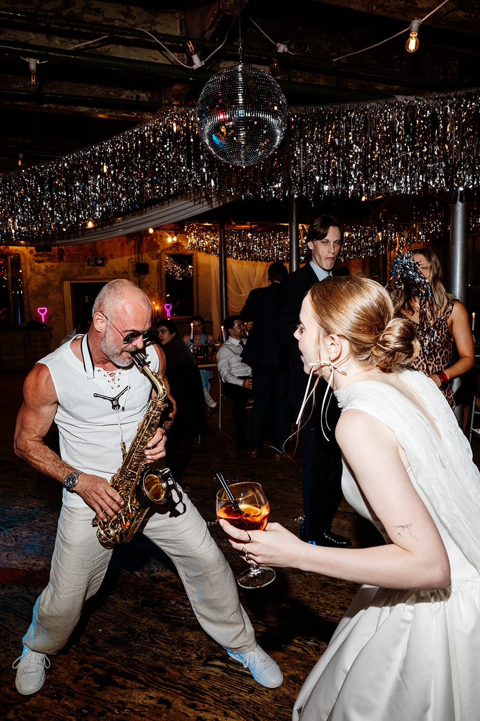 Paul Martyn playing saxophone in front of the bride under a disco ball