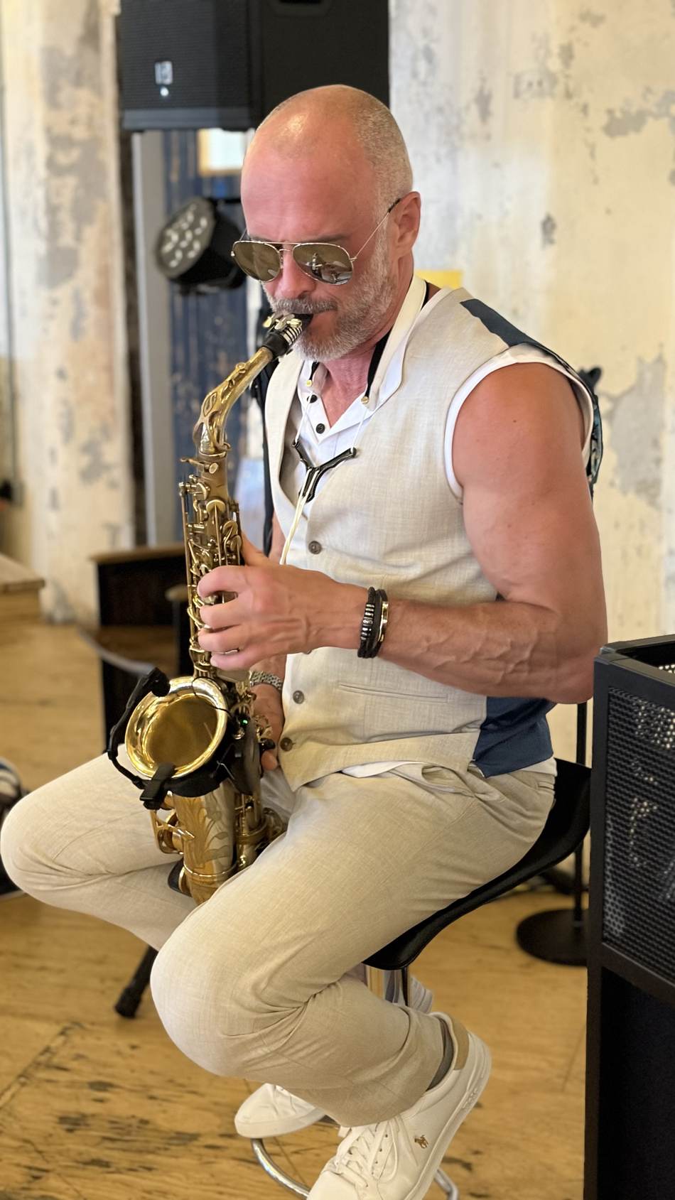 Paul Martyn seated playing saxophone at an outdoor venue