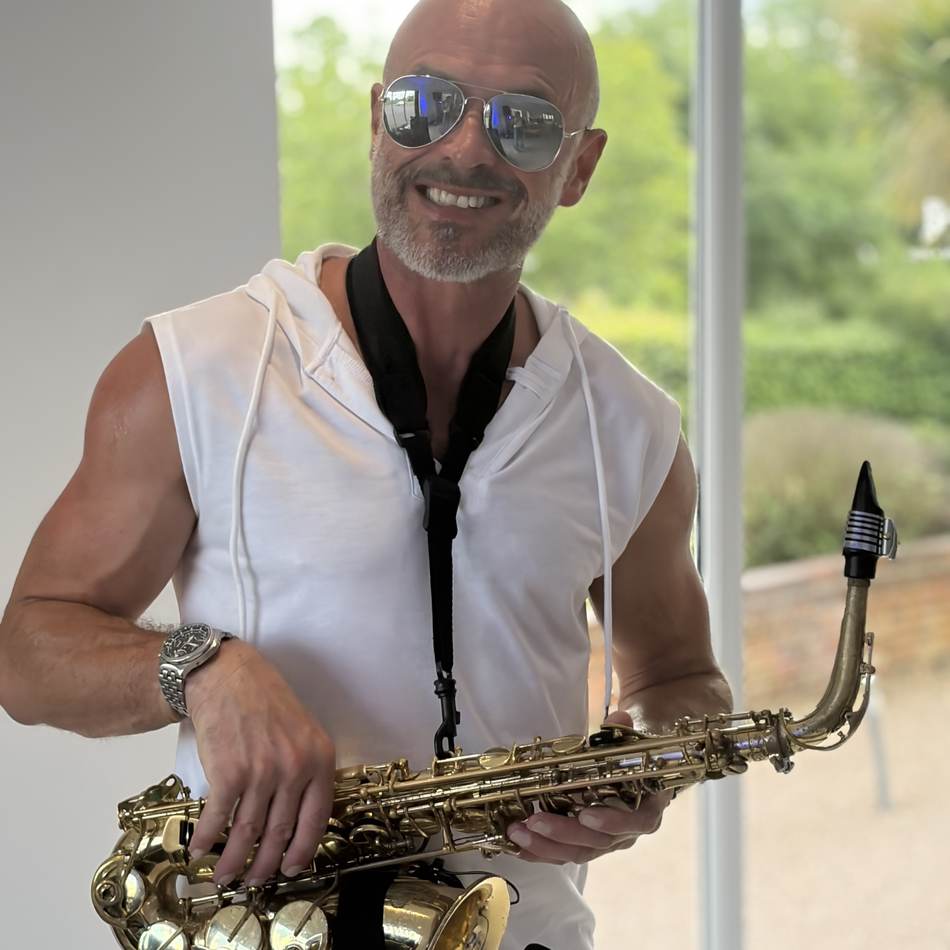 Paul Martyn playing saxophone under a marquee with string lights